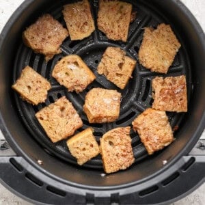 Pieces of bread being toasted in an air fryer basket.