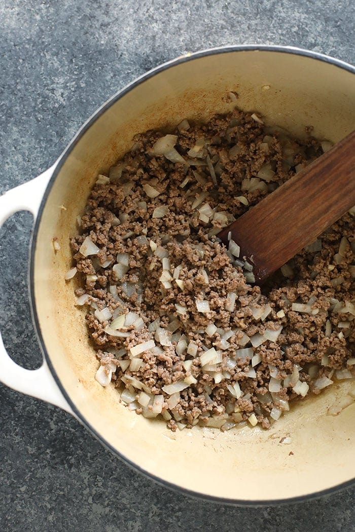 The best chili recipe you'll ever eat is right here! Our beef chili is made with ground beef, beans, diced tomatoes, and DIY chili seasoning. beef and onions in stockpot.