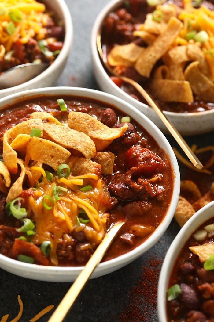 The best chili recipe you'll ever eat is right here! Our classic beef chili is made with ground beef, beans, diced tomatoes, and a homemade chili seasoning. bowl of beef chili with Fritos and shredded cheese.