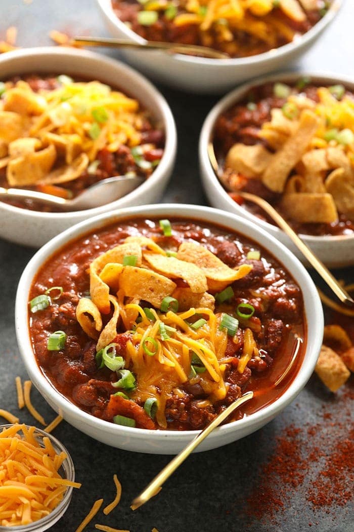 The best chili recipe you'll ever eat is right here! Our beef chili is made with ground beef, beans, diced tomatoes, and DIY chili seasoning. 4 bowls of beef chili with Fritos on top.
