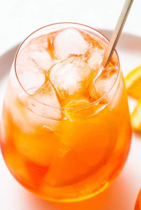 Aperol spritz in a glass with a straw.