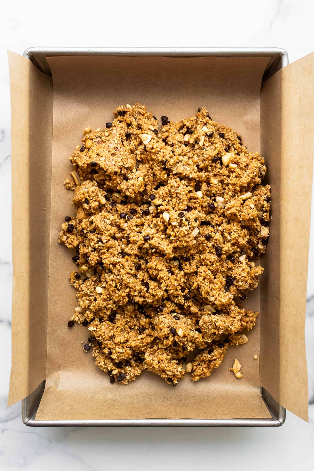 Want a healthy, protein-packed snack on the go? These no bake peanut butter bars will be your new favorite treat! They're crunchy, sweet, salty, and ridiculously easy to make. No bake peanut butter bar batter in a baking sheet.