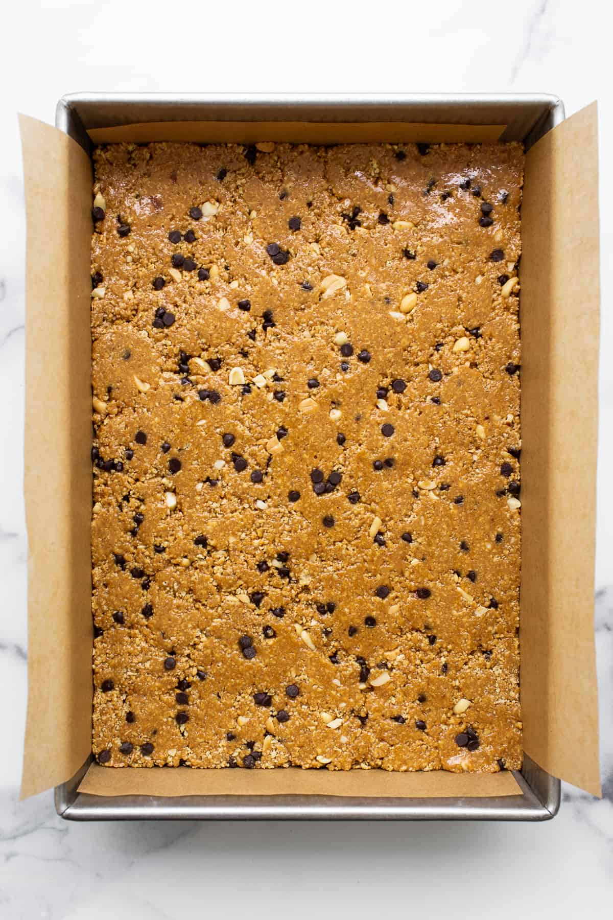 Want a healthy, protein-packed snack on the go? These no bake peanut butter bars will be your new favorite treat! They're crunchy, sweet, salty, and ridiculously easy to make. No bake peanut butter bars pressed into a cake pan.