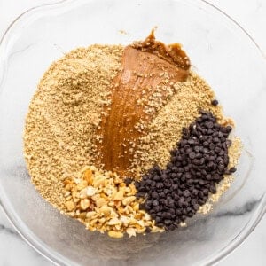 A glass bowl filled with ingredients for peanut butter granola.