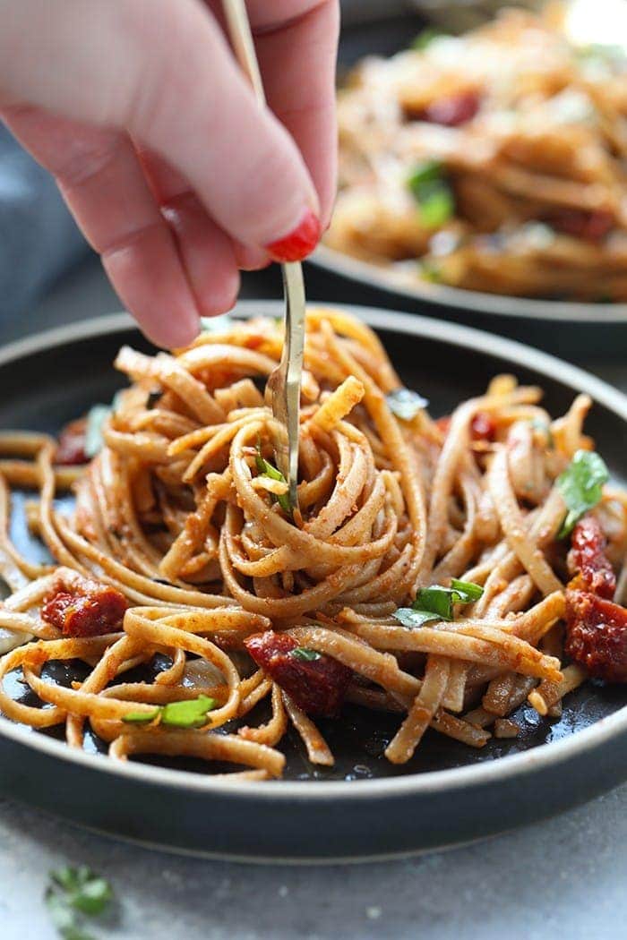 Pasta can be a healthy dinner packed with flavor and deliciousness. Substituting whole wheat pasta, adding vegetables, and creating a flavorful sauce is the key a healthy pasta for dinner. Treat yourself to this Whole Wheat Sun Dried Tomato Basil Pasta. It's light, fresh, and only require a few simple ingredients! sun dried tomato pasta with whole wheat pasta twirled on fork