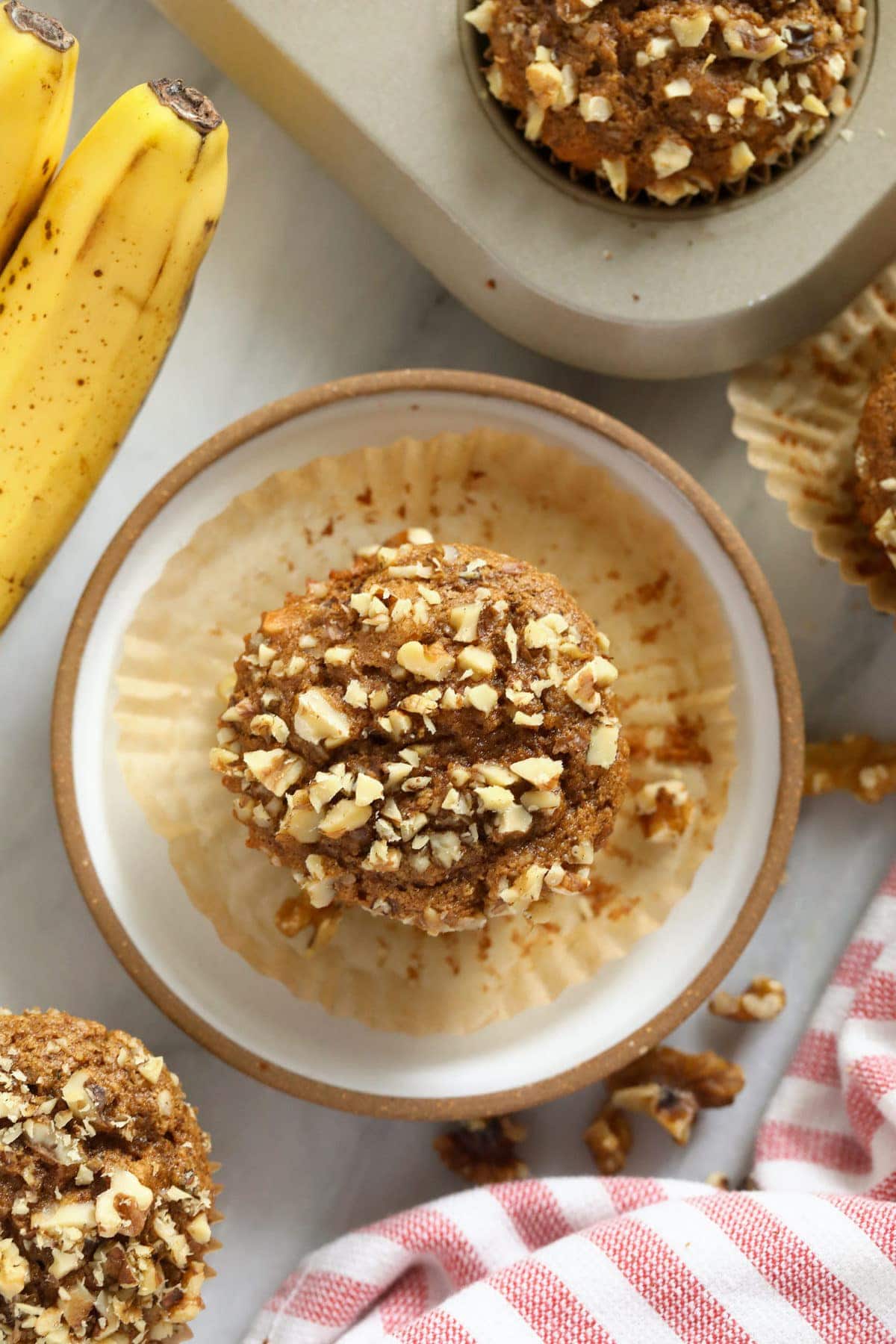 Banana nut muffins on a plate and in a muffin pan. 