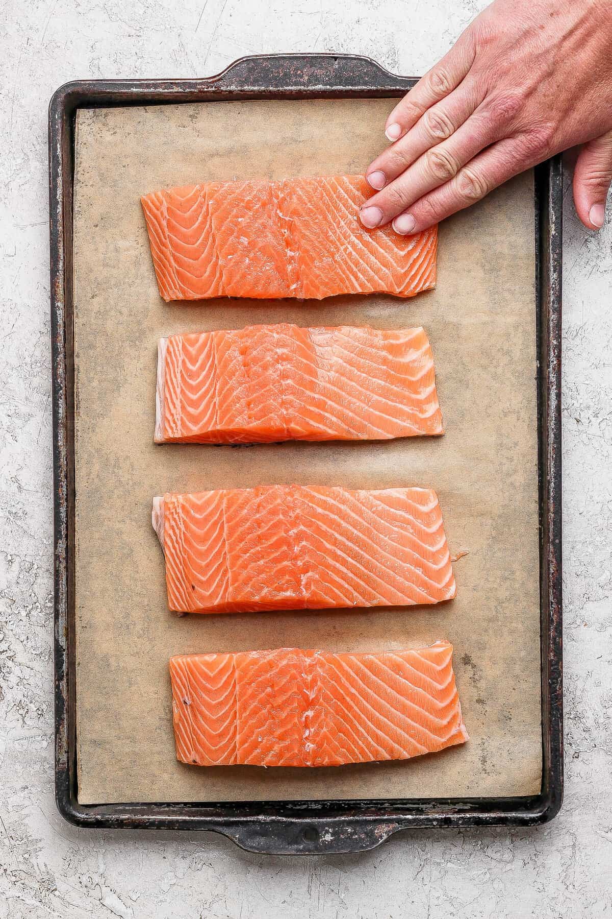 Seasoned salmon fillets arranged on a parchment-lined baking sheet ready for the broiler.