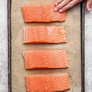 Seasoned salmon fillets arranged on a parchment-lined baking sheet ready to broil.