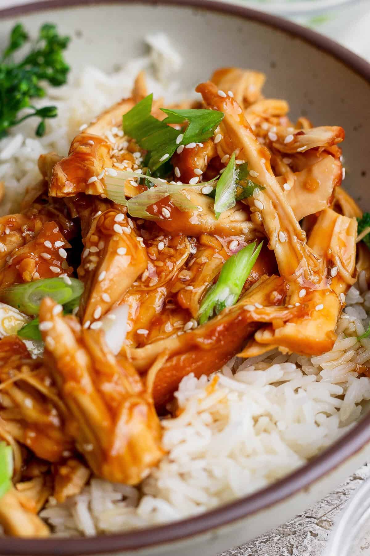 Honey garlic chicken over white rice garnished with sesame seeds and green onions