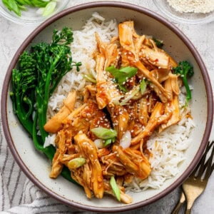 Crockpot honey garlic chicken rice bowl with broccolini, green onions, and sesame seeds
