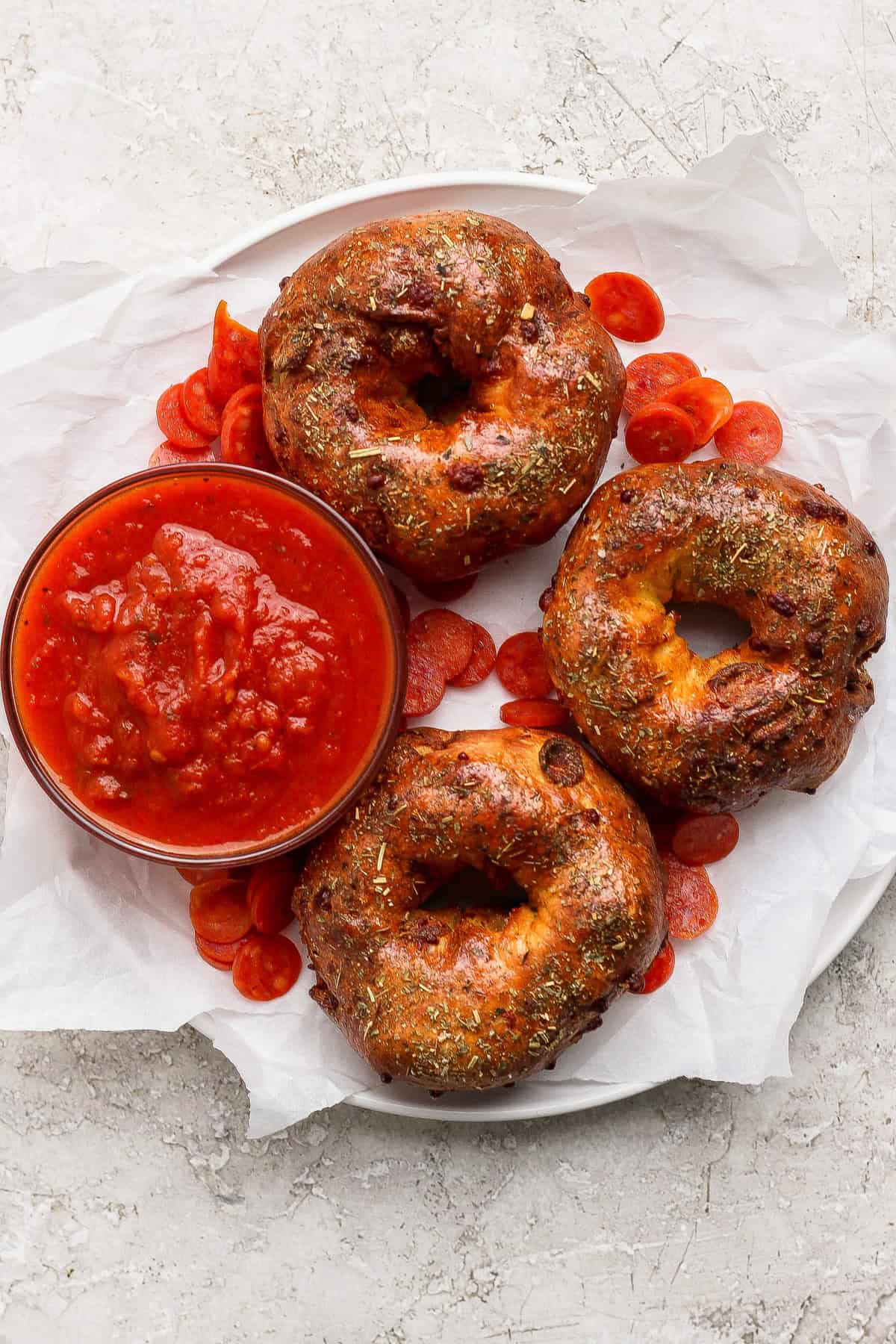 Overhead view of three baked pizza protein bagels with marinara sauce and pepperoni