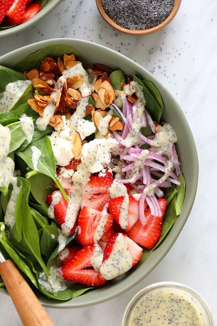 Strawberry spinach salad in a bowl topped with feta and candied almonds.