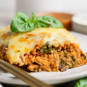 Slice of spinach quinoa lasagna casserole topped with fresh basil on a plate