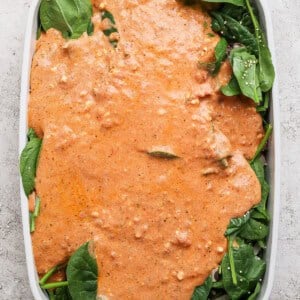Layering cottage cheese sauce over fresh spinach in a baking dish