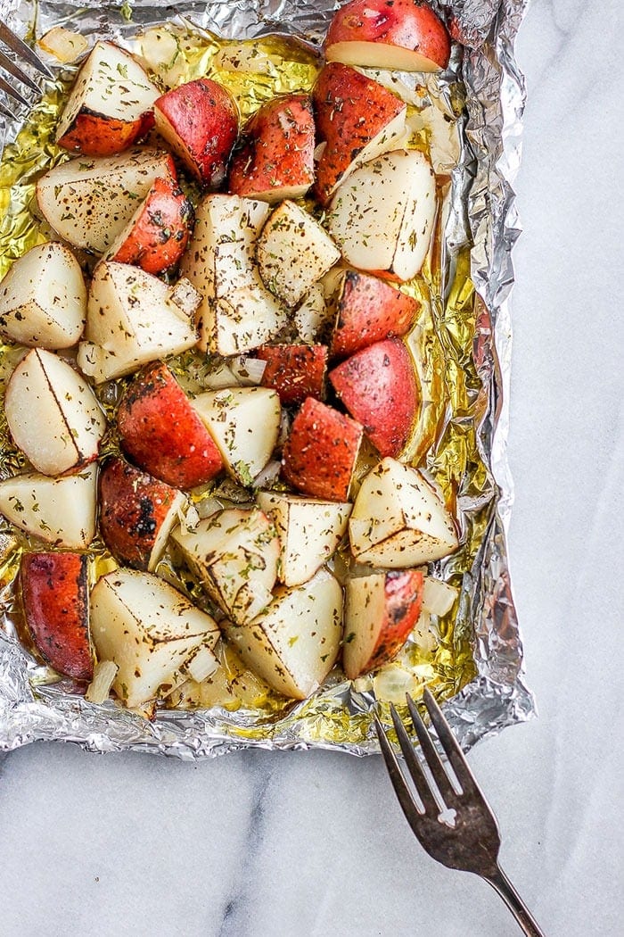 These grilled potatoes in foil are crispy, perfectly seasoned, and ready in just 30 minutes. My go-to easy side dish for summer grilling! red potatoes on tin foil covered in olive oil and spices