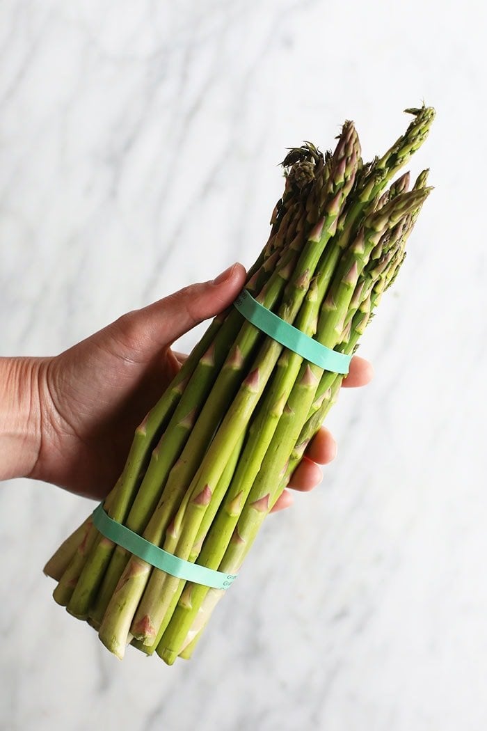 a bundle of fresh asparagus spears on a cutting board