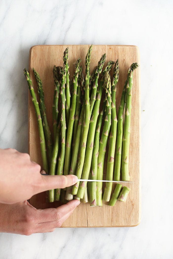 trimming the woody ends off asparagus spears with a knife