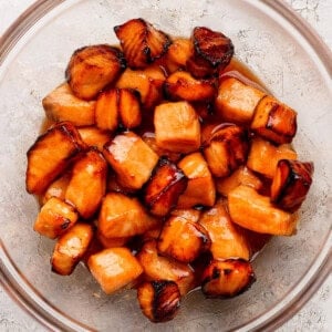 Cubes of cooked salmon in a glass bowl, coated with a shiny, dark caramelized glaze.