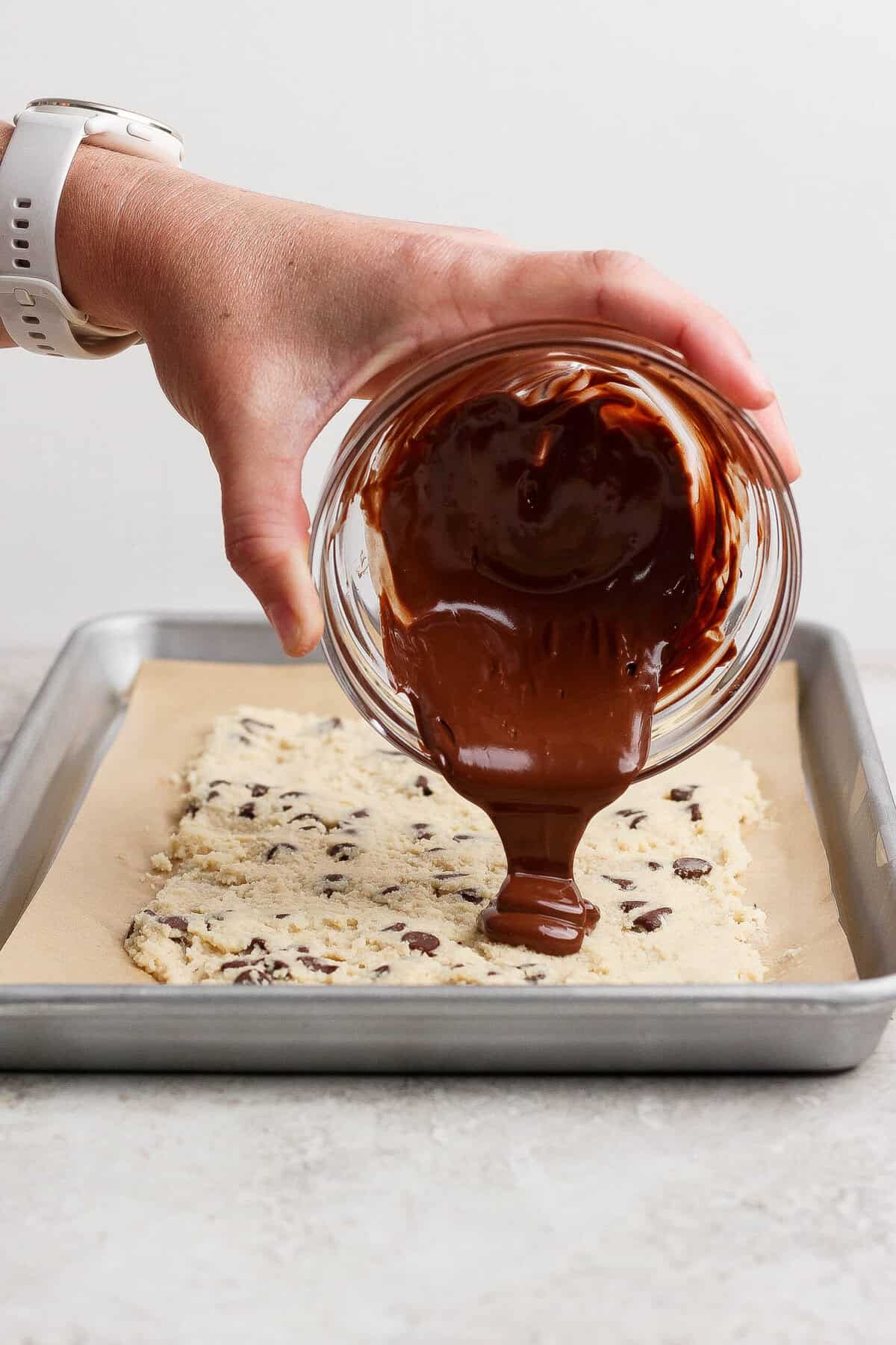 pouring melted chocolate over frozen cottage cheese cookie dough bark