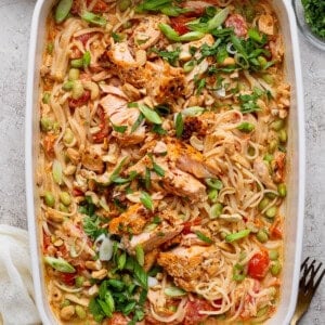 Salmon casserole with rice noodles, baked salmon chunks, cashews, green onions, cilantro, and chili crunch Boursin sauce in a white baking dish