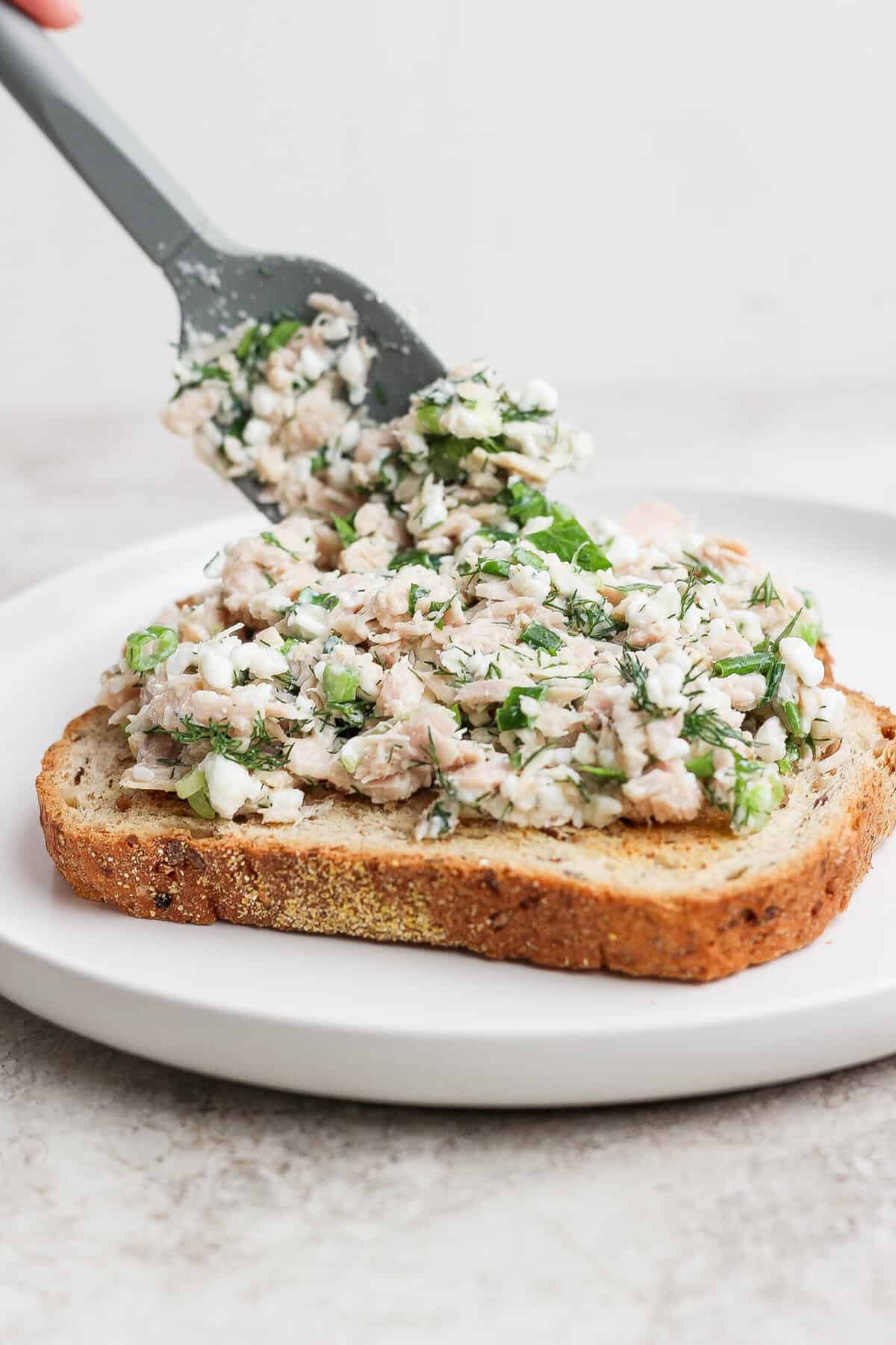 spreading cottage cheese tuna salad on sourdough toast