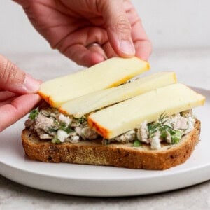 placing muenster cheese slices on tuna melt