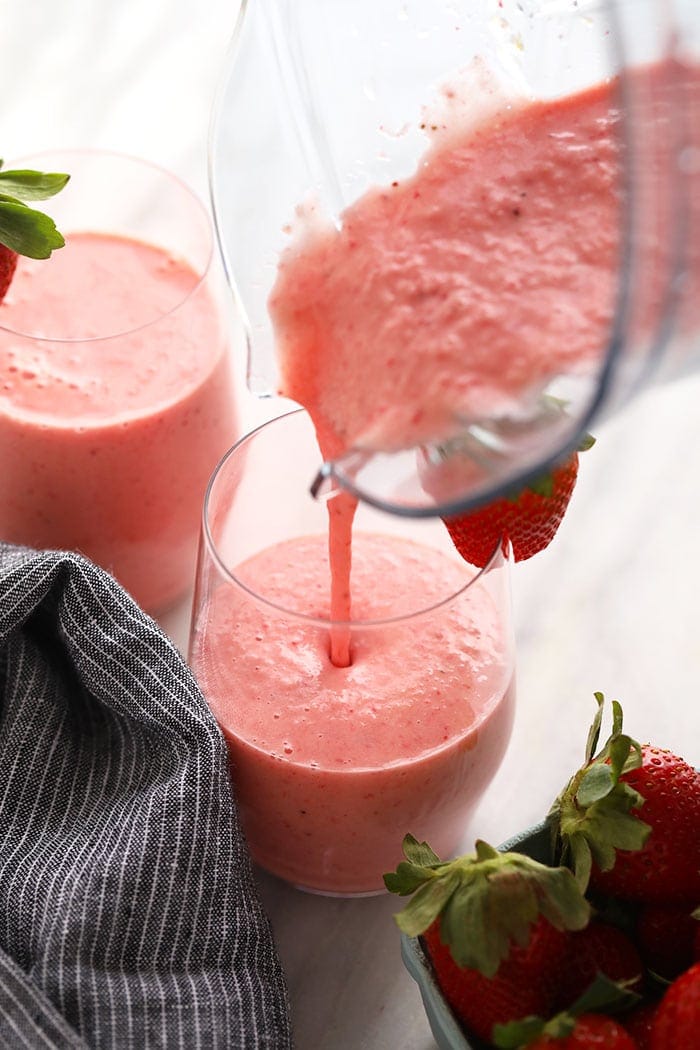 Wake up to this refreshing strawberry smoothie recipe. With just 4 basic ingredients you can have a cafe-worthy creamy strawberry smoothie ready to go in less than 5 minutes. Strawberry smoothie being poured into a glass.