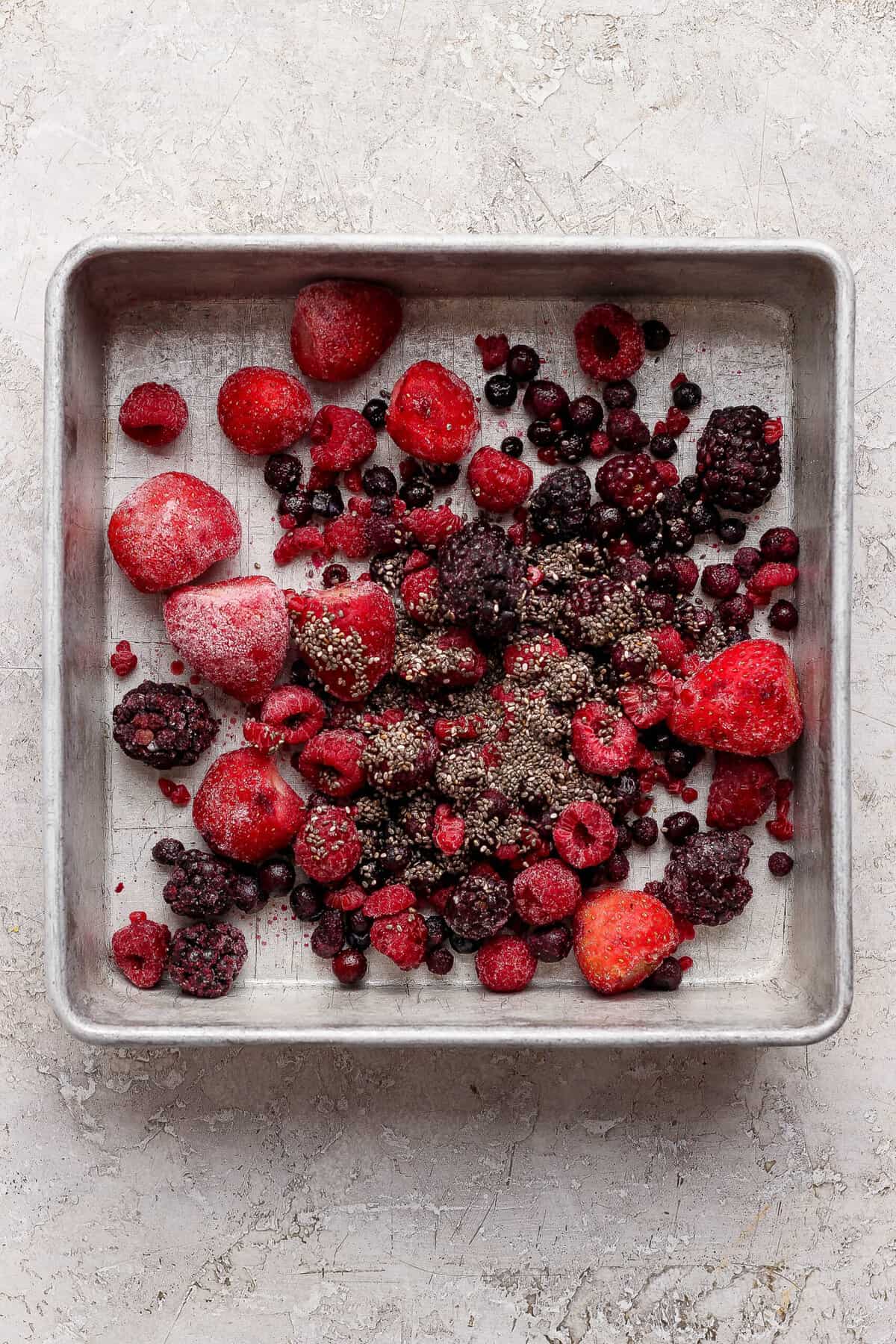 frozen mixed berries tossed with chia seeds spread in a baking pan for protein berry crumble