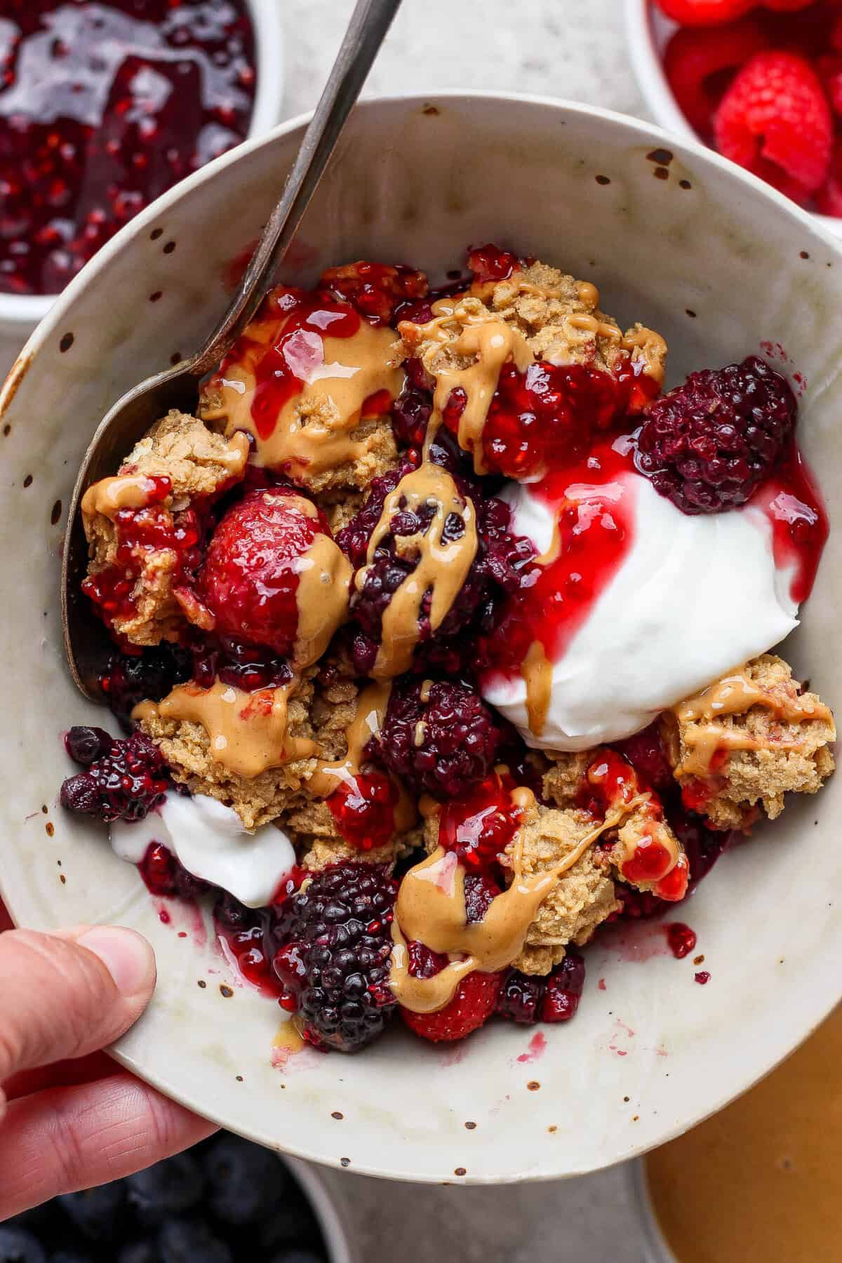bowl of protein berry crumble with yogurt blackberries strawberries and peanut butter drizzle