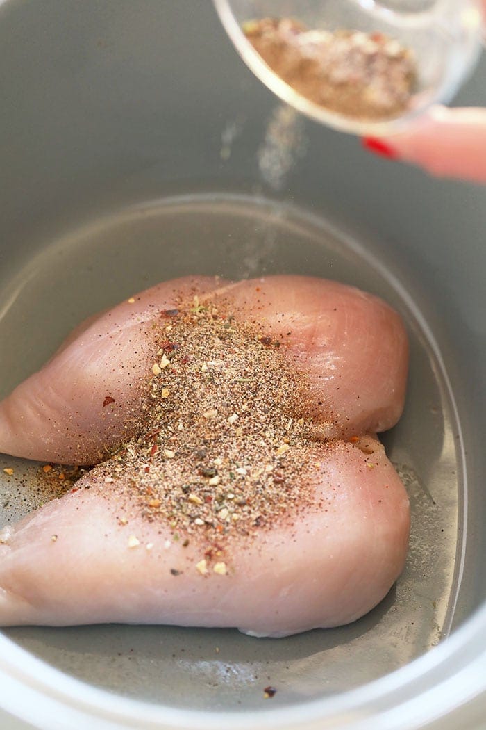 raw chicken breasts seasoned with dry rub in slow cooker