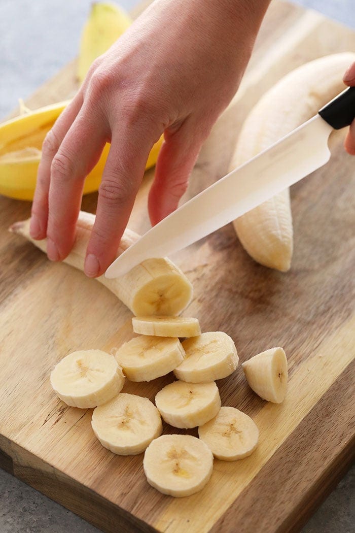 a person freezing bananas on a cutting board
