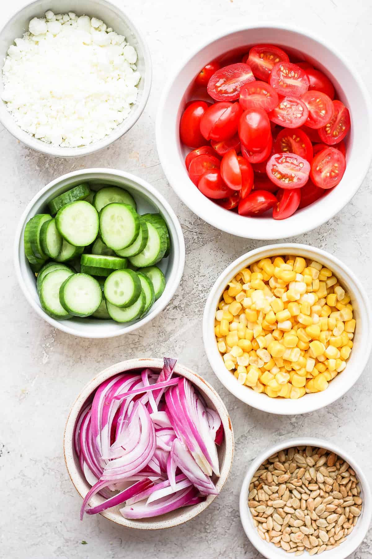 Seriously delicious steak salad made with perfectly grilled steak, avocado, tons of veggies, and an herby vinaigrette dressing. steak salad ingredients in bowls.