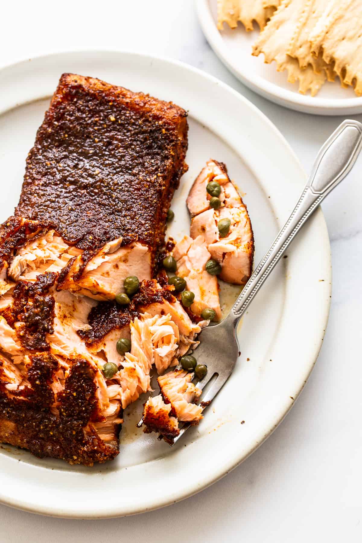 This perfectly tender and flakey smoked salmon is made with a simple dry rub and a yummy maple glaze making it perfect for crackers, bagels, or a salad! forking salmon filet.